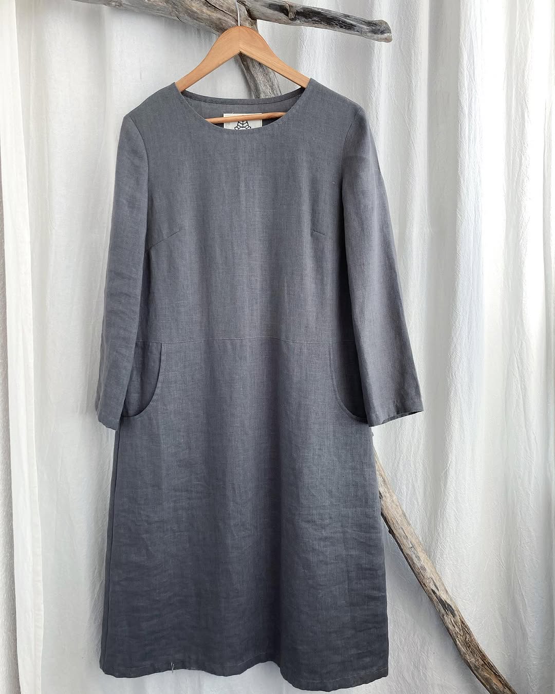 Graues ODOMARI Leinenkleid auf einem Holzbügel